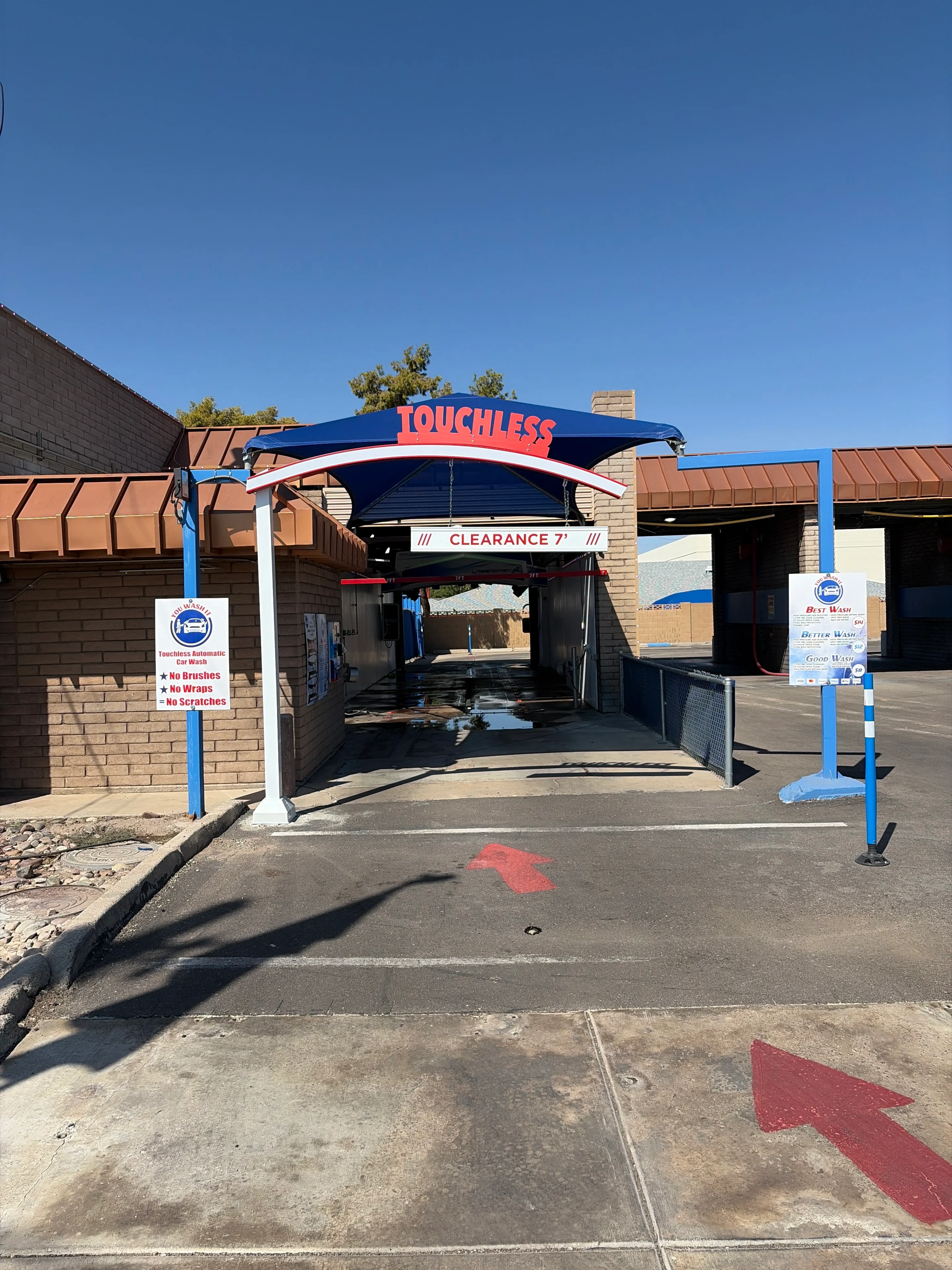 Touchless car wash entrance under clear sky.
